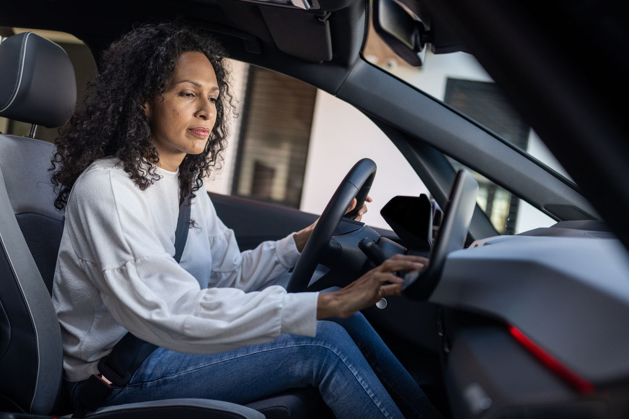 Side view of mature woman using global positioning system while driving her car.