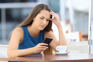 Single worried woman watching a mobile phone and waiting for a call or message sitting in a coffee shop