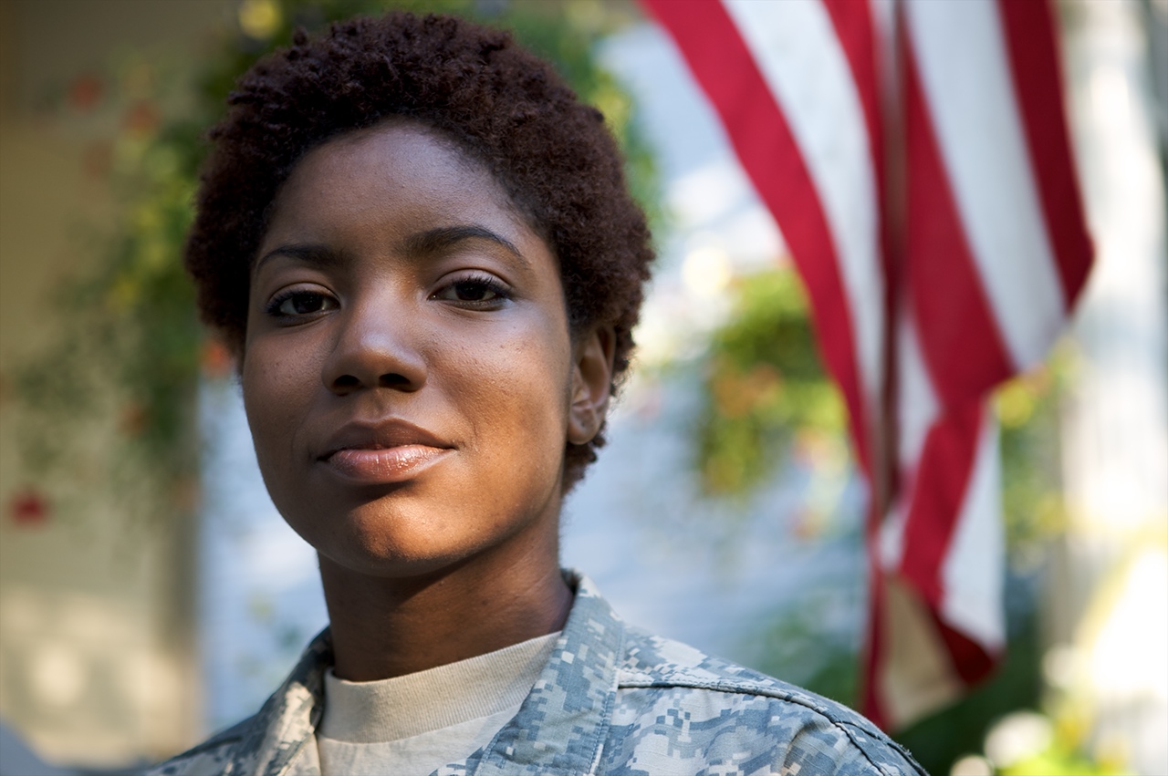Portrait of a African American Soldier in Uniform with flag in background.