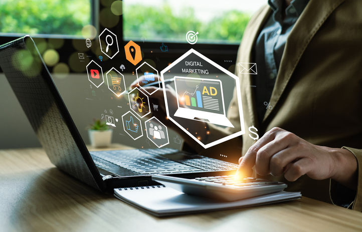 man at laptop with finger on calculator with digital marketing icons overlaid on image