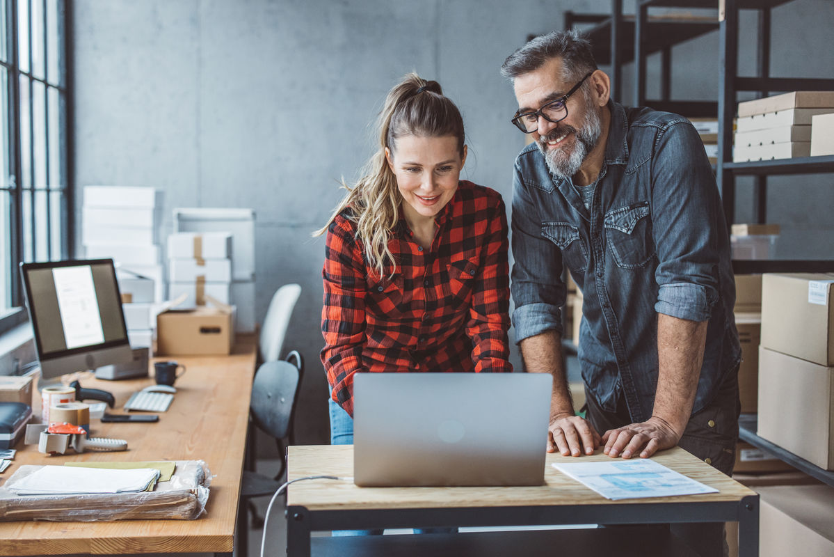 Older male business owner showing younger female how to run business 
