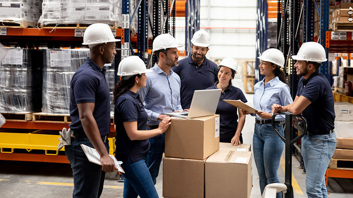 group of workers in warehouse meeting together