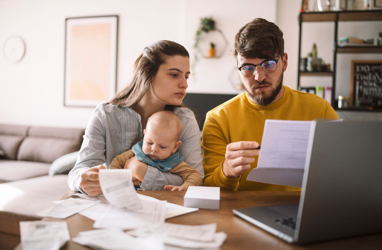 Young family with baby worried about family budget and high taxes and bills. Inflation concept.