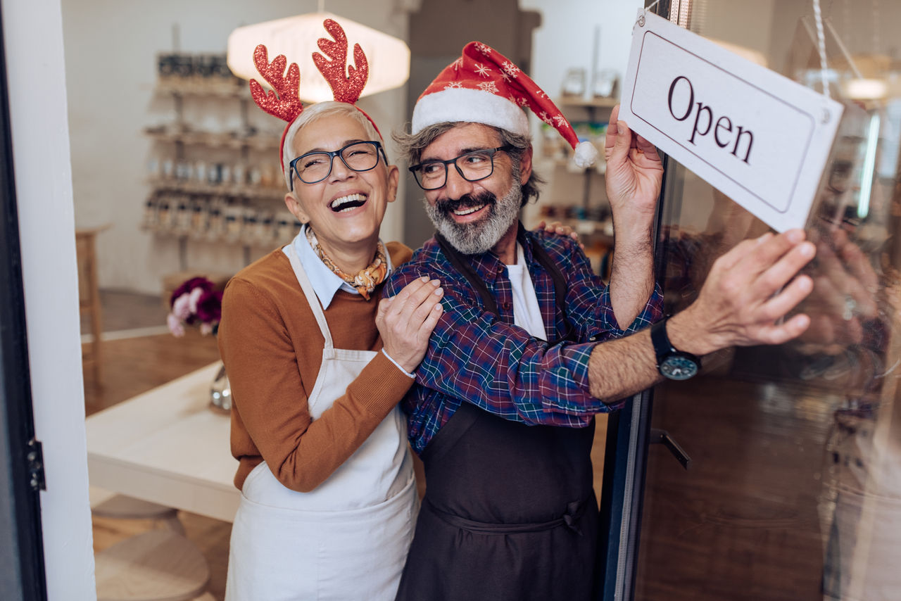 Mature man and woman opening their shop for Christmas.
