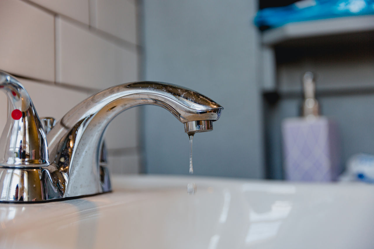 A leaking sink faucet, in a bathroom of a residential home. When you take care of things, they last, don't wait to fix a problem like a pipe or leaking faucet otherwise it can be a costly home repair.