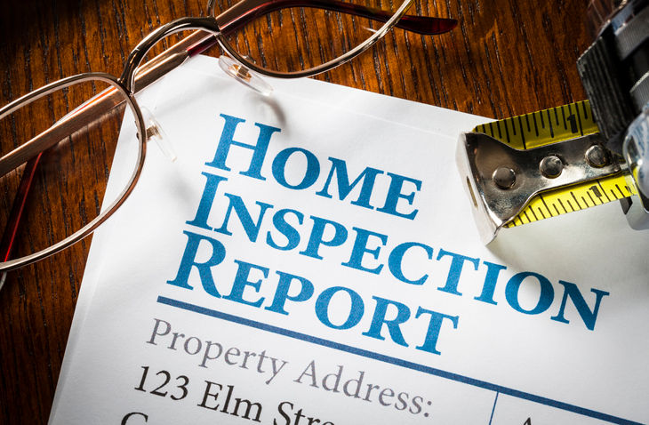 Home Inspection Report with measuring tape and glasses on desk