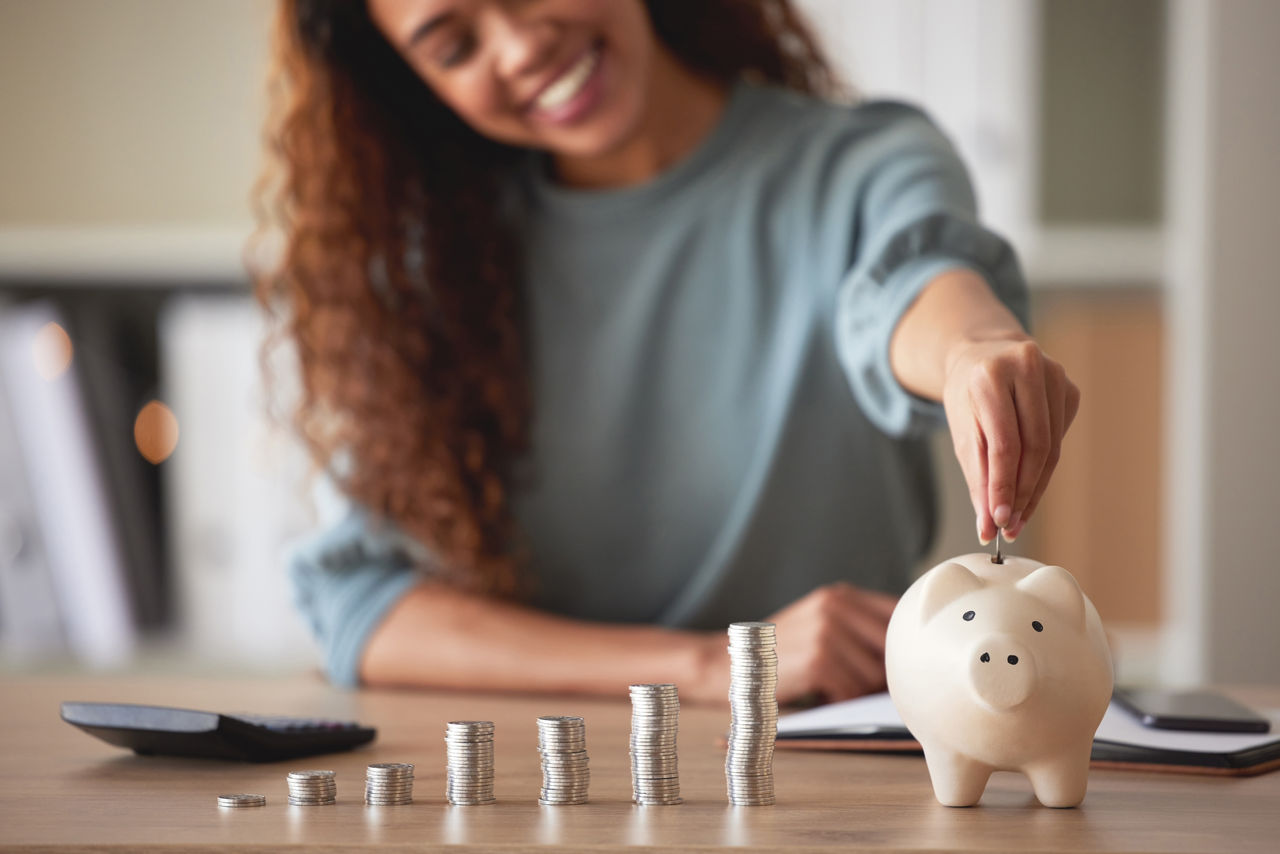 Show the top half of a white piggy bank with coins going into it