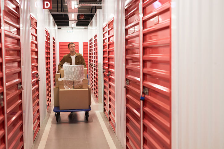 Man pushing cart with boxes when searching for rented unit in self-storage facility