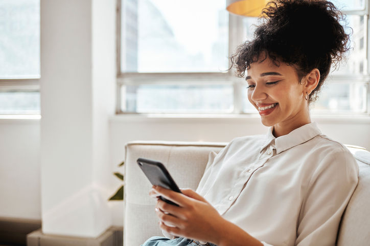 Phone, relax and woman on social media for happy online content or internet entertainment on house sofa. Smile, digital or young girl enjoys texting, chat or typing a post while reading global news