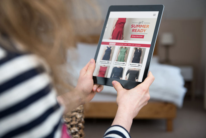 A woman is shopping on a digital tablet on a shopping website on the internet. Screen content is photographer's own design/imagery.