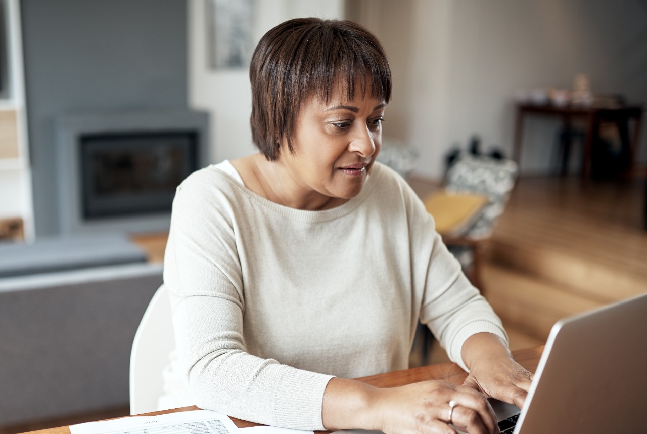 Cropped shot of an attractive senior woman sitting alone and using a laptop in her living room at home