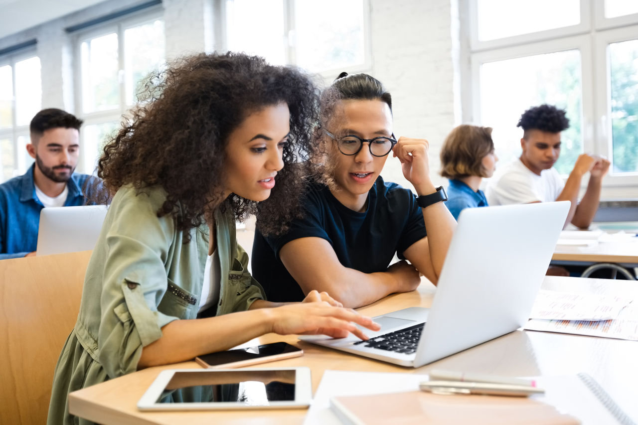 Young happy couple shopping online, sitting at home. Beautiful African American woman holding credit card, attractive man booking tickets, ordering food on website