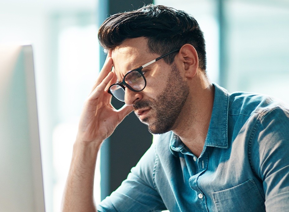 A worried looking man holding his head