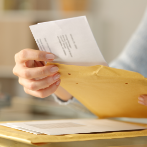 Woman opening envelope and pulling paper out.