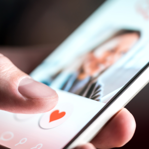 Man's hand holding cellphone looking at dating app