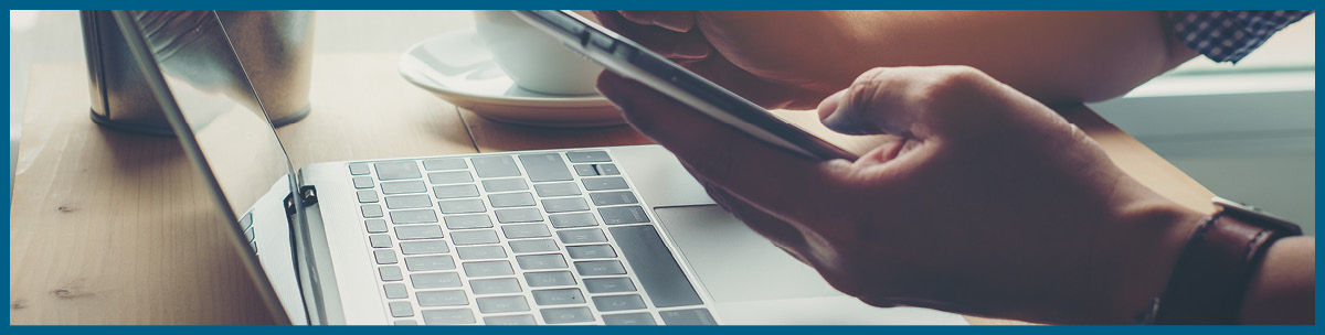 close up of laptop on desk with person holding smartphone