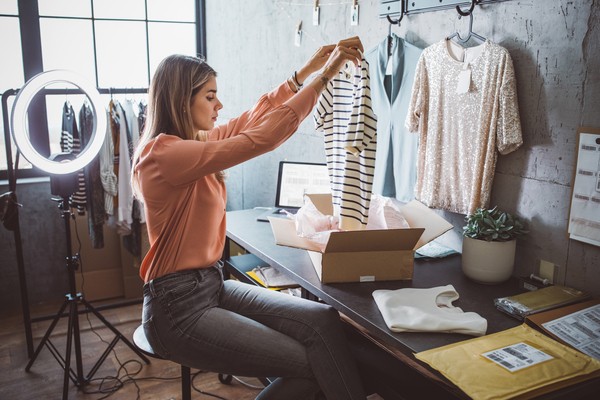 Young woman at online shop. She is owner of small online shop. Receiving orders and packing boxes for delivery.