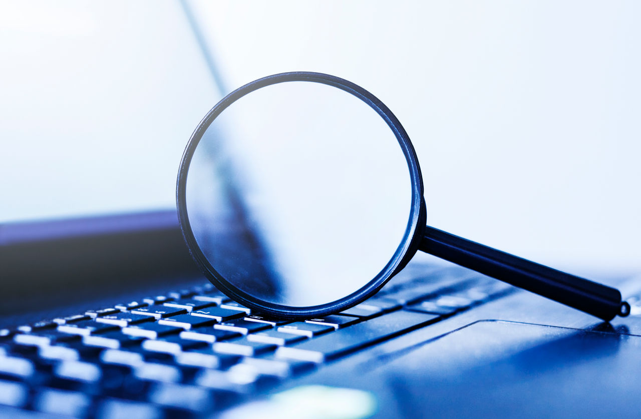 Laptop computer with magnifying glass, concept of search