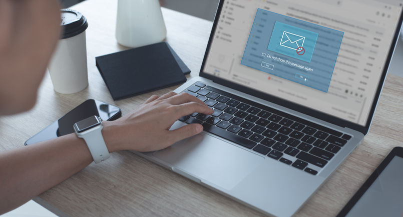 Blocking spam e-mail, warning pop-up for phishing mail, network security concept. Business woman working on laptop computer at home with warning window on screen