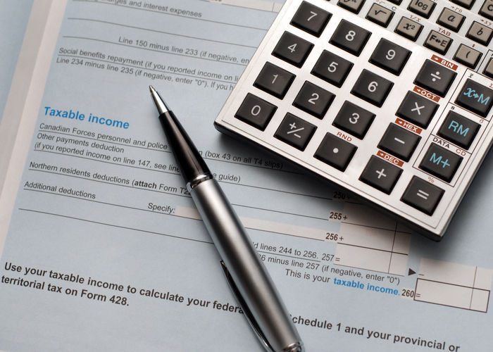 Close up of a calculator and pen on a Canadian tax form.  See also