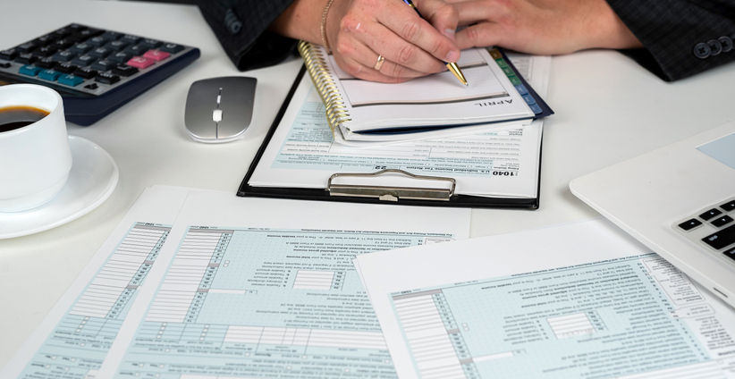 close up of male hand filling US tax form. Accountant working with 1040 form. April, tax for time