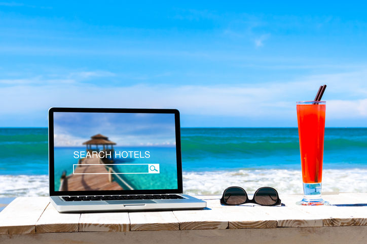 Search hotels website on computer screen, online booking concept, tropical beach background