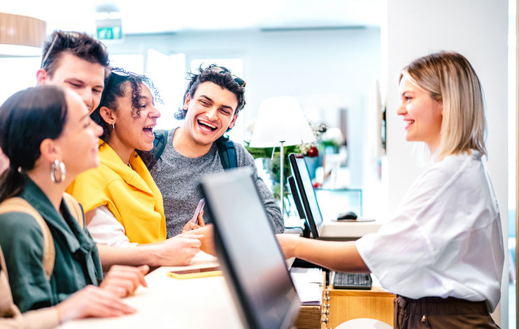 Young diverse friends having fun time at luxury hotel reception on check in time - Travel life style concept with happy people waiting at guesthouse desk on fancy vacation - Bright vivid filter