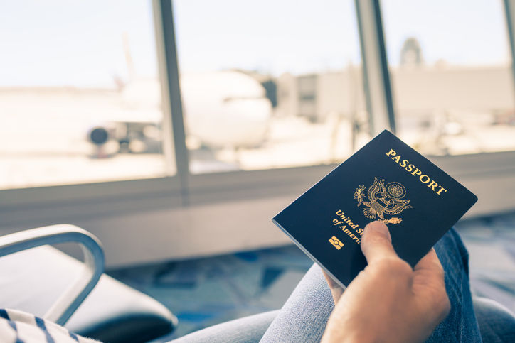 Traveler at airport holding United States passport in hand.