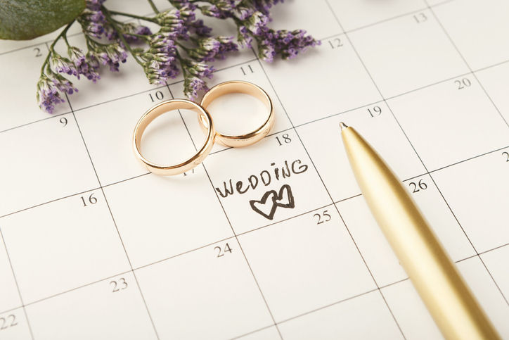 Word wedding, two hearts and gold rings on calendar with sweet purple flowers. Love, invitation, advertisement, romantic background concept, copy space