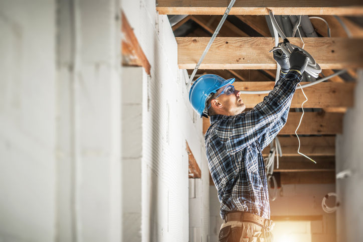 Professional Caucasian Electrician Working on Electrical Wiring System Installation in New Residential House Ceiling.