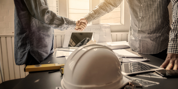 two people shaking hands hard hat in foreground