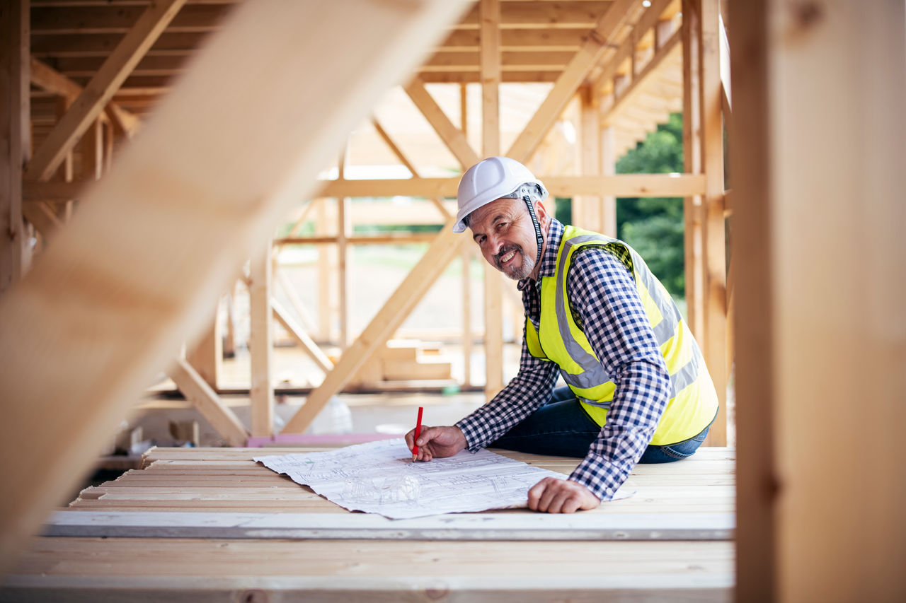 Smiling architect portrait in construction site, ecology wooden construction site.