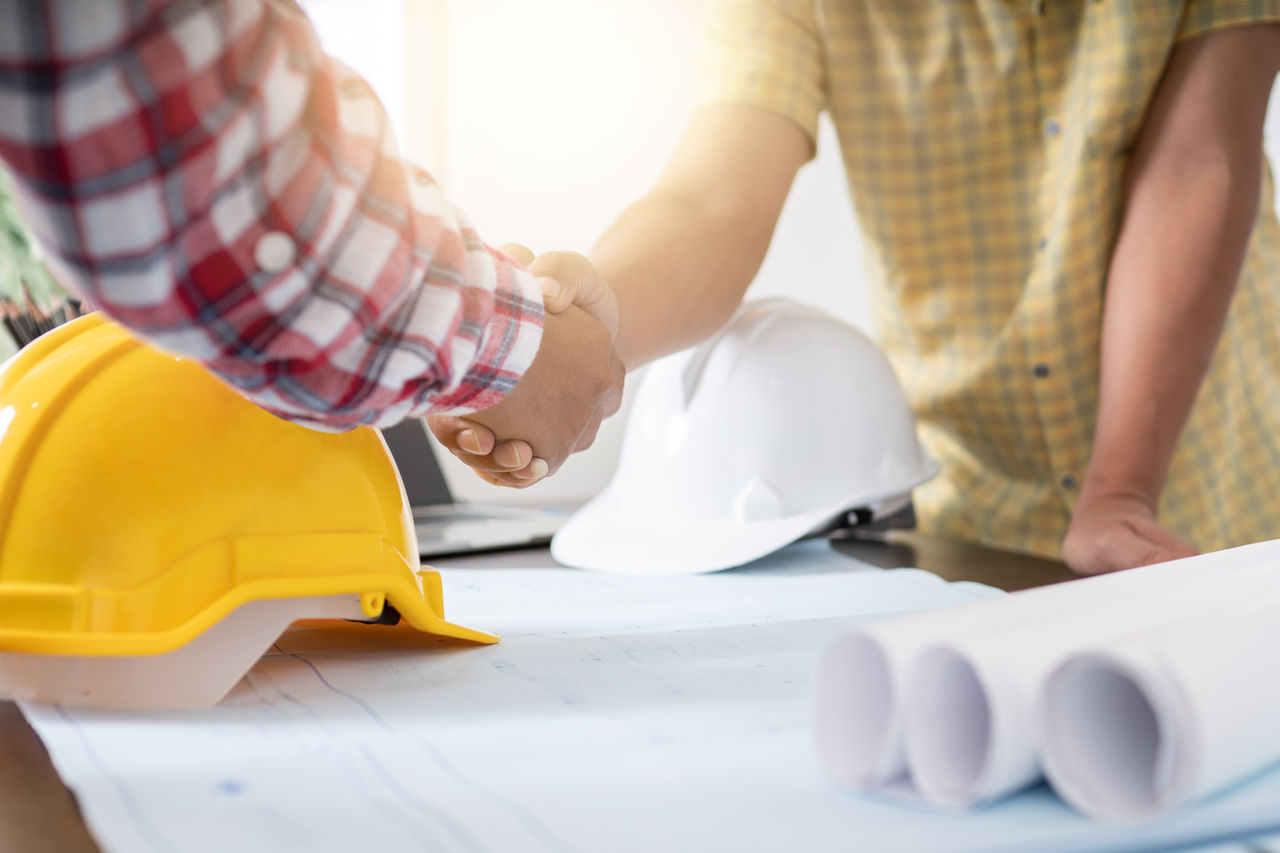 Successful deal and cooperation concept, Architect and engineer construction workers shaking hands while working with building contractor in office