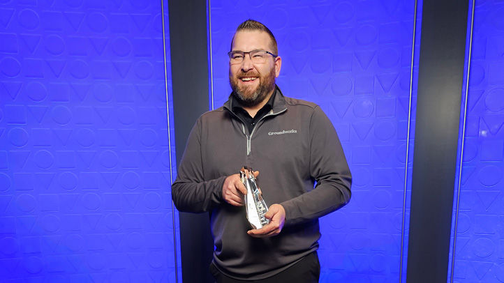 Owner of Groundworks holds up his 2024 Torch Award with a big smile
