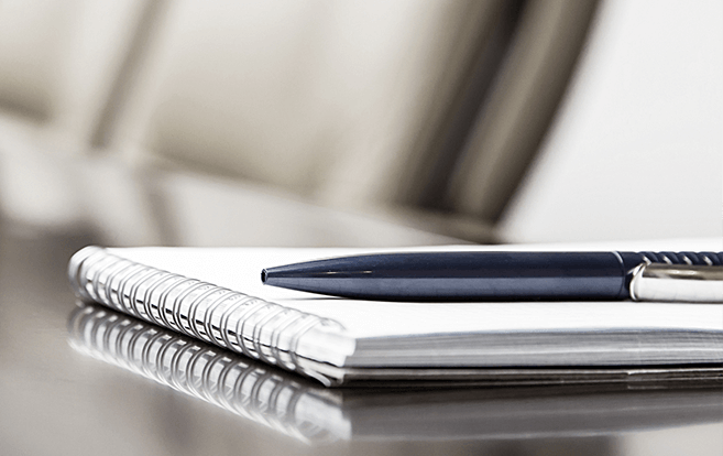 Notebook and pen sitting on board meeting table