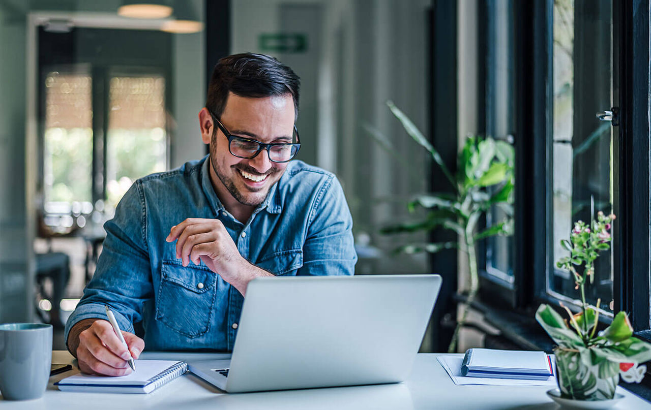 Man smiling at his computer at a desk