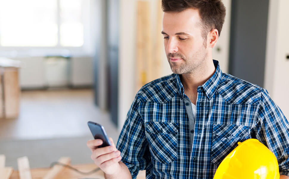 Contractor looking at phone on job site