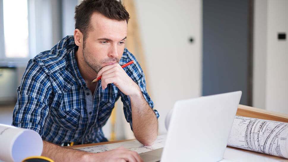 Contractor looking at his laptop at job site desk