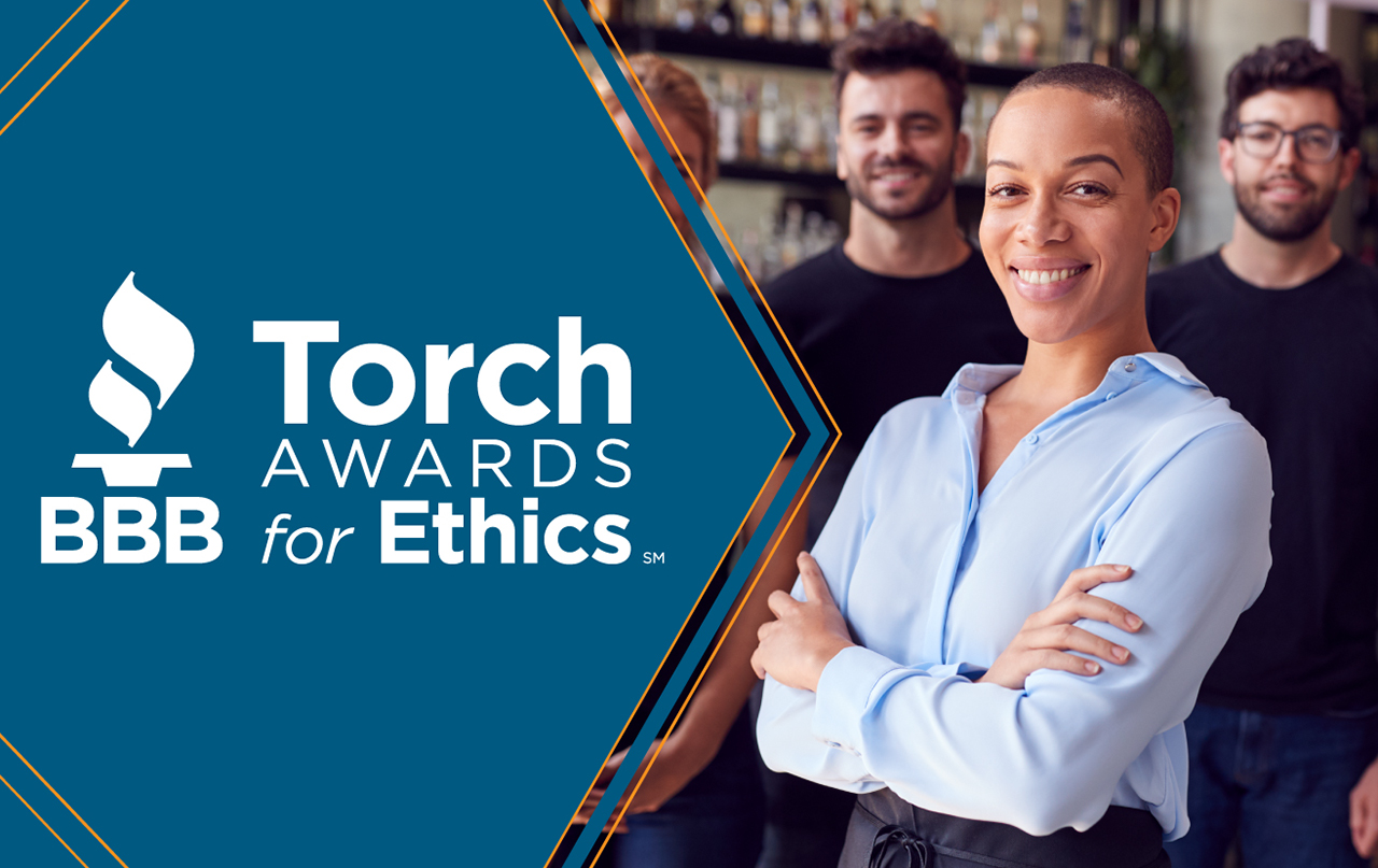 Business people applauding a team member with the white BBB Torch Awards logo over a dark blue background 