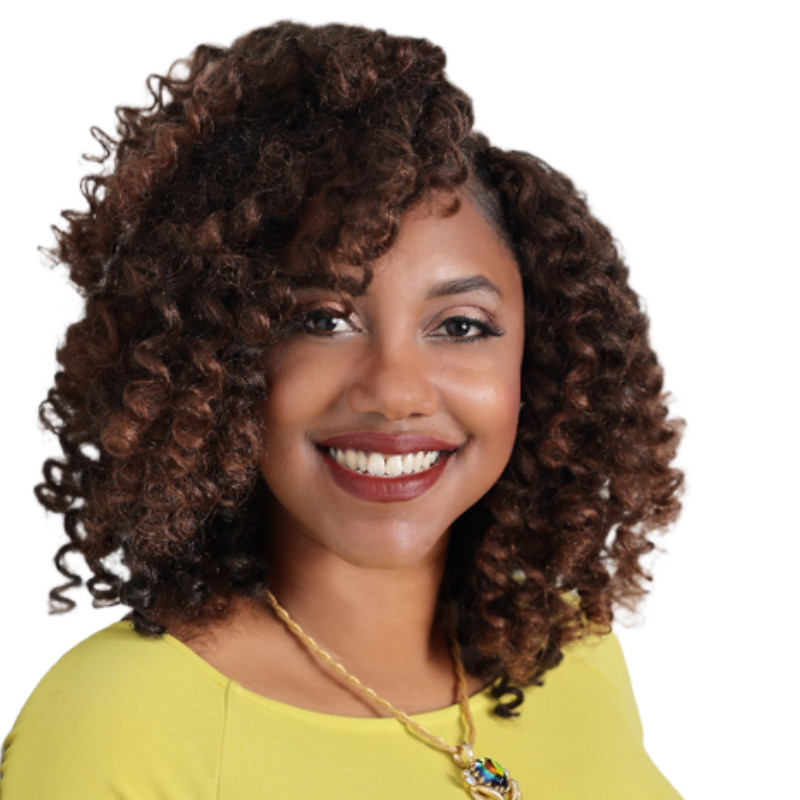 Woman with dark curly hair and brown eyes smiling and wearing a yellow shirt and necklace