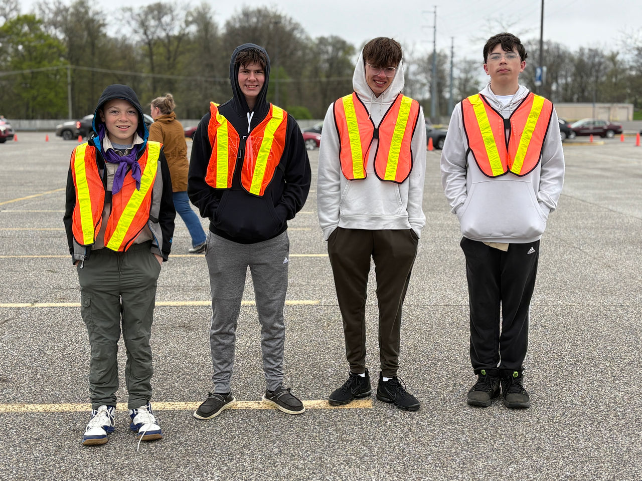 4 smiling teenaged boys wearing orange vests