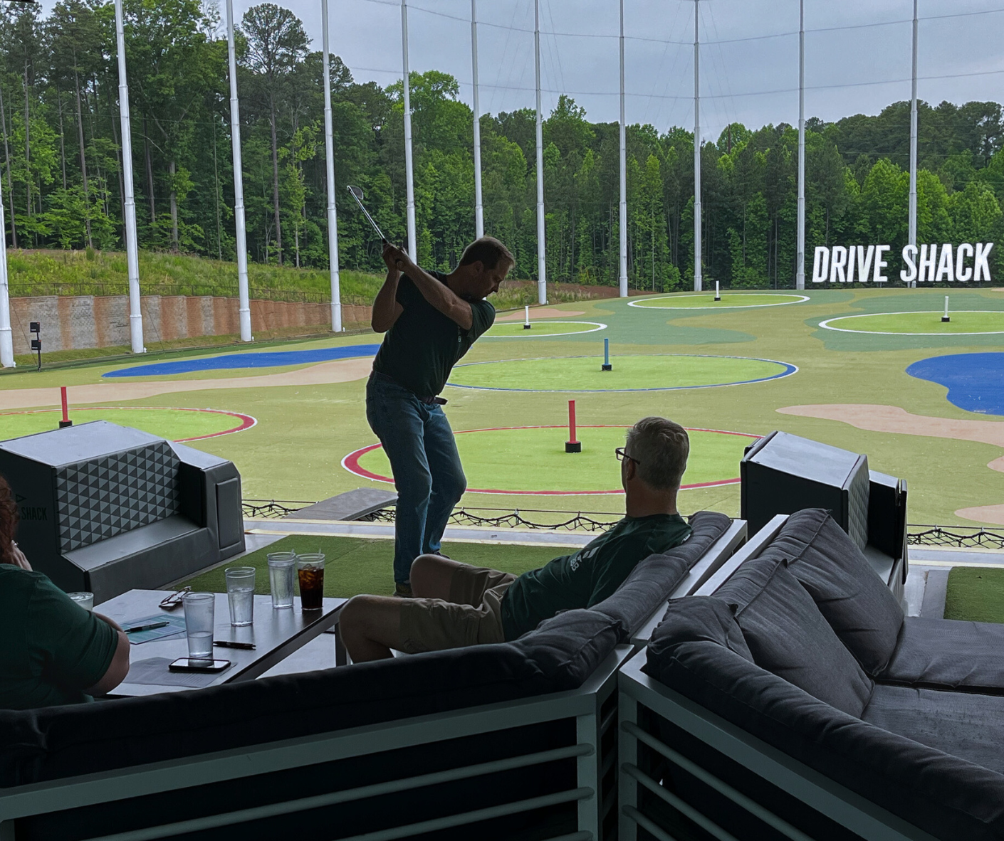 Individual golfing in front of the Drive Shack logo at the BBB Golf Tournament.