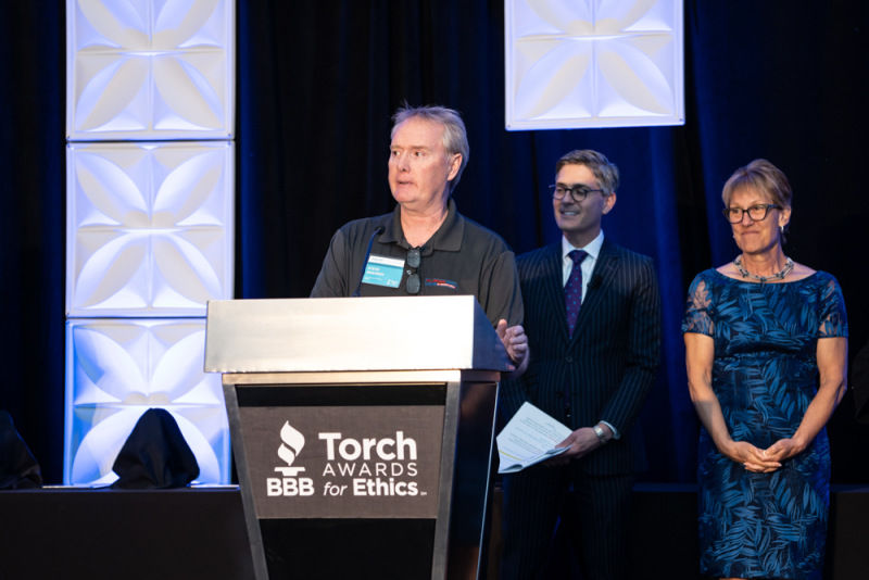 COO of Flooring Expo by Carpet King speaks on stage at podium of BBB Torch Awards for Ethics
