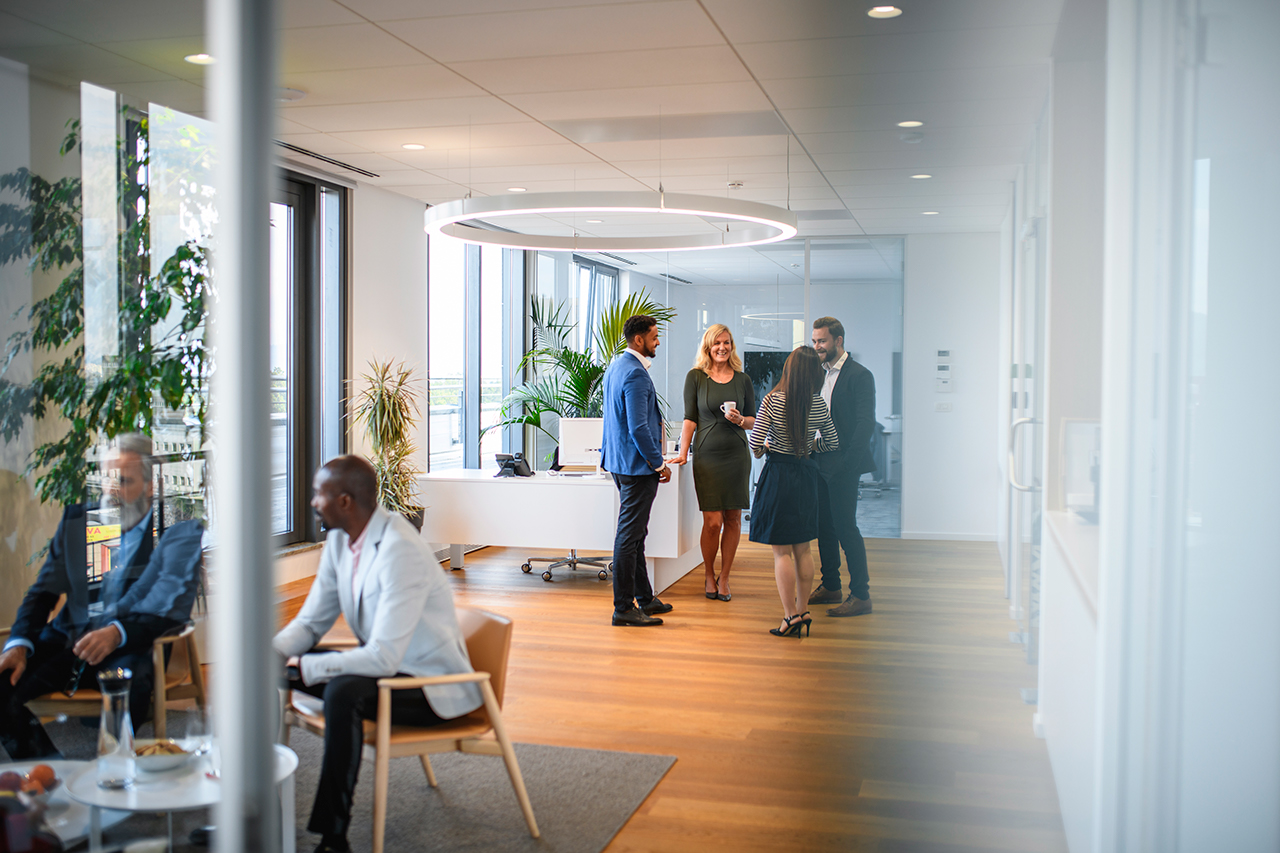 Distant viewpoint of business executives enjoying conversation with diverse colleagues during break from seminar.