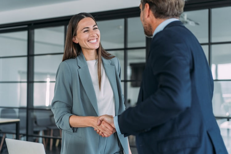 Business people shaking hands in modern office. Shot of businessman and businesswoman handshaking during a meeting in the office.