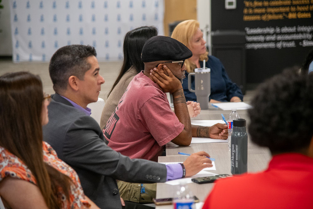 Row of adults at a table writing notes.