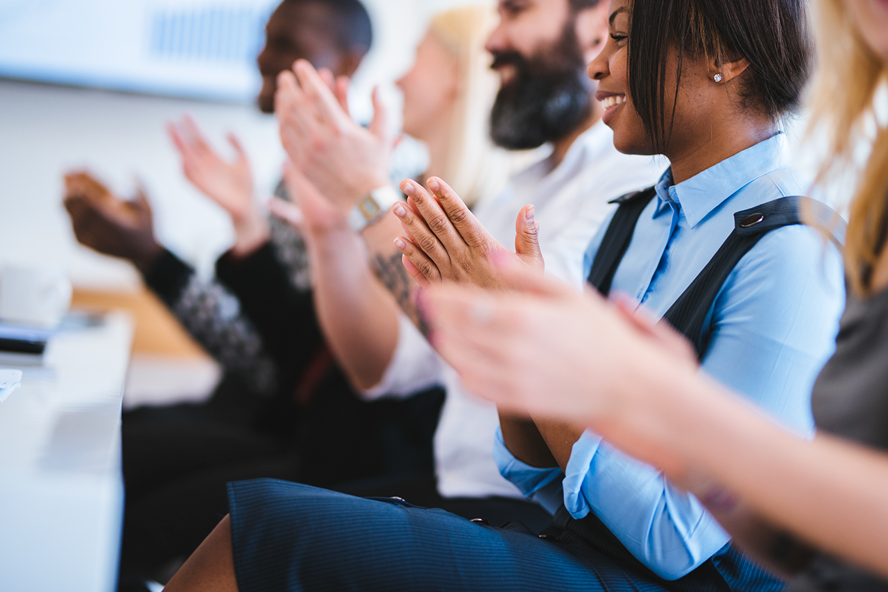 Shot of group of people clapping in a conference hall.