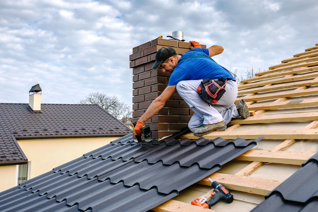 a professional master (roofer) with electric screwdriver covers repairs the roof