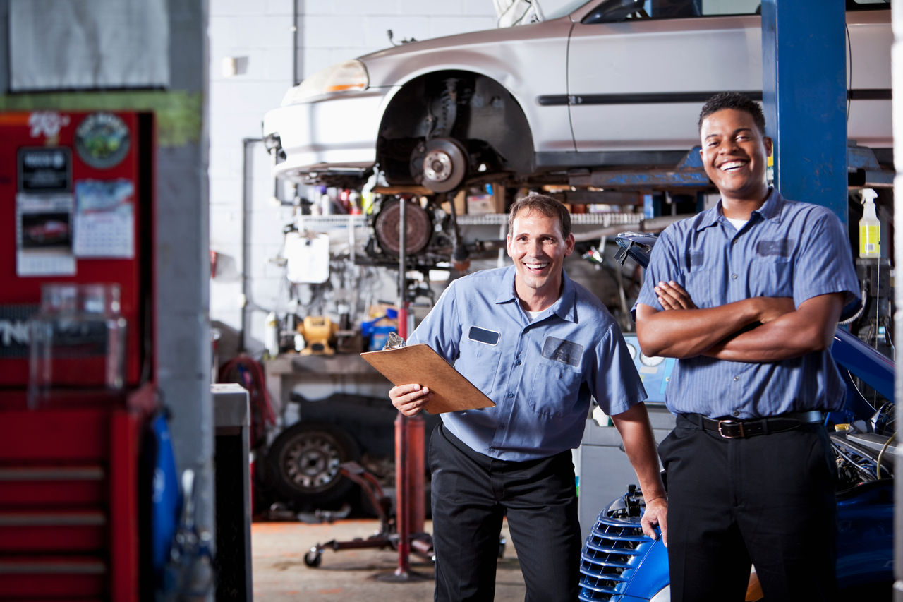 Multi-ethnic auto mechanics in repair shop.  Focus on Caucasian man (40s).