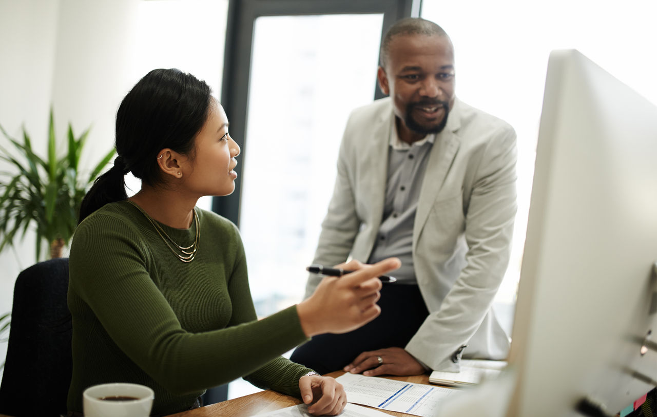 Shot of a businesswoman and businessman using a computer together in a modern office